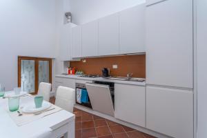 una cucina con armadi bianchi, tavolo e sedie di Ricasoli Garden Modern Apartments a Udine
