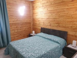1 dormitorio con 1 cama en una pared de madera en Il Biancone en Champdepraz