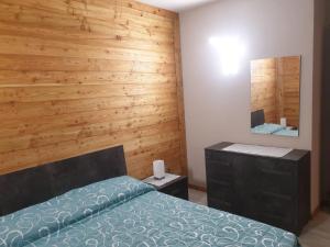 1 dormitorio con 1 cama y pared de madera en Il Biancone en Champdepraz