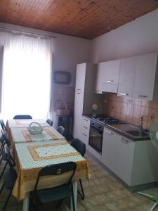 cocina con mesa y cocina con armarios blancos en I Nuovi Orizzonti Casa Girasole, en Calatabiano