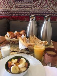 una mesa con un plato de comida y un bol de fruta en Chez Ichou, en Aït Idaïr