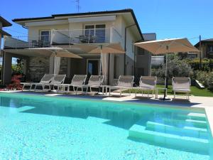 una casa con piscina con sillas y sombrillas en COSTA DEL GARDA - Lazise, en Lazise