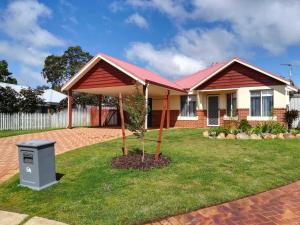 a house with a tree in the front yard at Stableford Cottage Holiday Home Dunsborough in Dunsborough