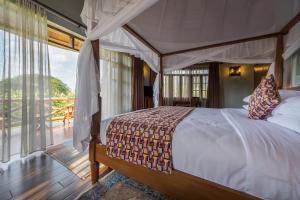 a bedroom with a canopy bed and a balcony at Emburara Farm Lodge in Mbarara
