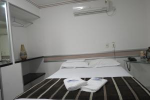 Una cama con dos toallas blancas encima. en Tirol Praia Hotel, en Natal