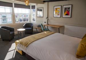 a bedroom with a large bed and chairs and windows at The Kings Arms Hotel in Malmesbury