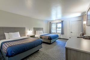 a hotel room with two beds and a desk at The Gunnison Inn at Dos Rios Golf Course in Gunnison