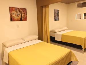 Habitación de hotel con 2 camas con sábanas amarillas en Apartamento Santa Isabel, en Santa Rosa de Cabal