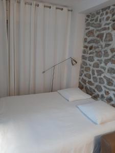 - un lit blanc avec une lampe à côté d'un mur en pierre dans l'établissement Villa des iris, à Paris