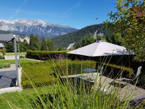 een witte paraplu in een tuin met bergen op de achtergrond bij Carrera - Ferienhaus mit Traumgarten (120m2) für max. 2 Personen in Valendas