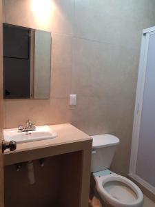 W łazience znajduje się umywalka, toaleta i lustro. w obiekcie Casa en Mahahual cerca de la playa w mieście Mahahual