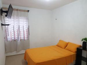 1 dormitorio con cama con sábanas de color naranja y ventana en Casa en Mahahual cerca de la playa, en Mahahual