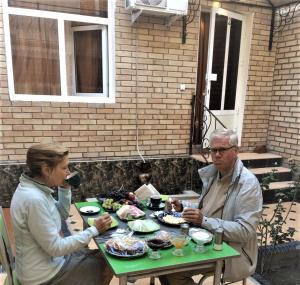 a man and woman sitting at a table with food at Khalima in Bukhara
