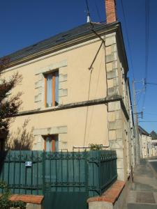 uma casa com uma cerca verde em frente em Les Trois Puits em Brion-près-Thouet