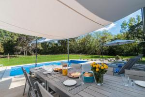 einen Tisch mit Essen und einen Regenschirm auf einer Terrasse in der Unterkunft Villa Stepančić - large garden and heated pool in Labin