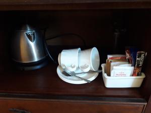 um armário de madeira com um bule de chá e um bule de chá em Thokazi Royal Lodge em Nongoma