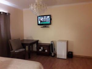 a bedroom with a table and a tv on the wall at Thokazi Royal Lodge in Nongoma