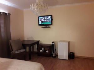 1 dormitorio con mesa y TV en la pared en Thokazi Royal Lodge, en Nongoma