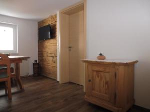 a room with a wooden door and a table and a room with a television at Gästehaus Grath in Lindenberg im Allgäu