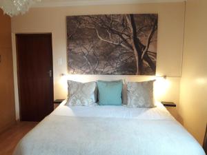 a bedroom with a large bed with a painting on the wall at Thokazi Royal Lodge in Nongoma