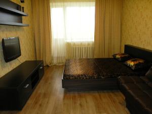 1 dormitorio con 1 cama, TV y sofá en Apartments on Buinskiy 1, en Ulyanovsk
