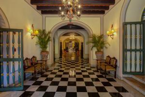 a hallway with a checkerboard floor and a chandelier at Hotel El Convento in San Juan