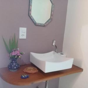 lavabo blanco en una encimera de madera con espejo en Casa Bela do Sol, en Isla de Boipeba