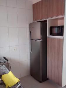 a kitchen with a stainless steel refrigerator and a microwave at Apartamento Boraceia 200 metros da praia, com ar condicionado in Bertioga +9 photos