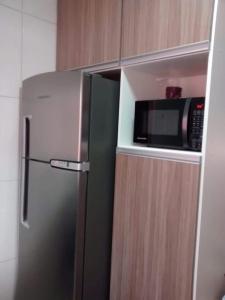 a microwave oven sitting on top of a refrigerator at Apartamento Boraceia 200 metros da praia, com ar condicionado in Bertioga