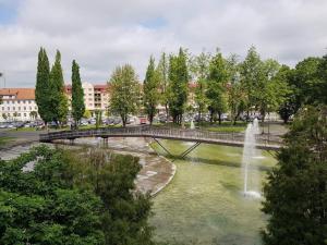 a bridge over a pond with a fountain at Parkova - pokoje hotelowe in Gołdap