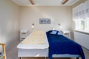 um quarto com uma cama com um cobertor azul em Borrgården Hostel em Ljusdal