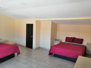 1 dormitorio con 2 camas con sábanas rojas en Motel Ranchito en Ensenada