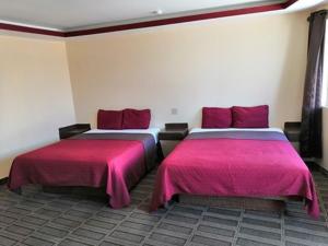 2 camas con colchas rosas en una habitación en Motel Ranchito en Ensenada