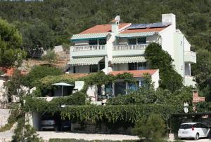a house on a hill with cars parked in front of it at Apartments Tonka - 10m from beach in Vinišće