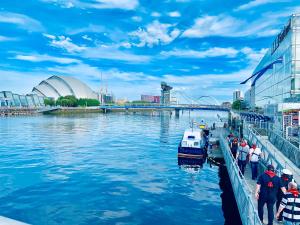 Ein Boot liegt an einem Fluss neben einem Gebäude vor Anker in der Unterkunft Glasgow City Centre - The PENTHOUSE with RiverViews - (Duplex, 3 Bedrooms, 3 Bathrooms, 2 Living rooms/Kitchen, Private SKY Terrace, 2 Parkings, Top Floor, Huge - 2100 sq ft, SECC HYDRO) in Glasgow