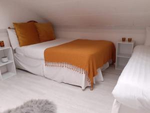 a white bedroom with a bed with an orange blanket at Vista Sol in Blackpool