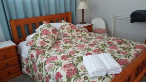 a bed with a floral bedspread and two towels on it at 59 Chaucer Apartment in Cambridge