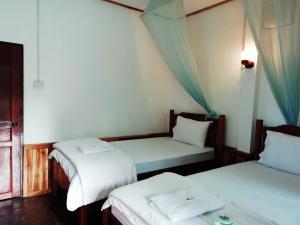 a room with two beds with white sheets at Sunset Bungalows & GH in Ban Ngoy-Nua