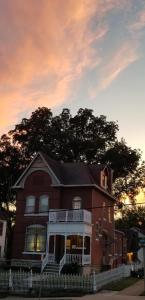 a large red brick house with a sunset in the background at Harbor Haus Inn & Suites in Hermann