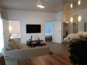 a living room with a couch and a tv on a wall at Modernes Apartment Metzingen in Mittelstadt