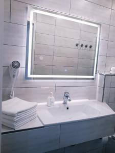 a bathroom with a sink and a mirror and towels at Modernes Apartment Metzingen in Mittelstadt