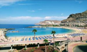 a beach with palm trees and a crowd of people at DELUXE 3 Rooms74m2,2Air Condit 2TV SEAVIEW on AMADORES,2 heatPOOLs, PARKING, 600 MB,Dishwasher,2Lift,,3 BEACHes in Playa del Cura