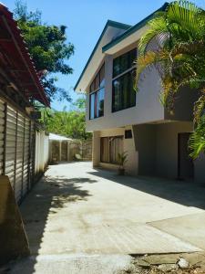 a house with a palm tree next to a driveway at Casa Playa Bahia Ballena de Osa in Uvita