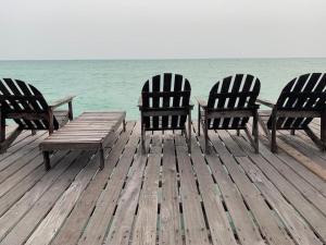 three chairs and a picnic table on a dock near the ocean at Spheredivers Scuba & Leisure in Pulau Mabul 