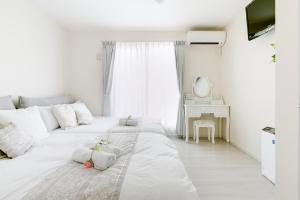een witte slaapkamer met 2 bedden en een spiegel bij Villa de Class in Osaka