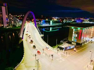 a bridge over a river at night with at Glasgow City Centre - The PENTHOUSE with RiverViews - (Duplex, 3 Bedrooms, 3 Bathrooms, 2 Living rooms/Kitchen, Private SKY Terrace, 2 Parkings, Top Floor, Huge - 2100 sq ft, SECC HYDRO) in Glasgow