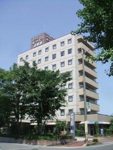 um edifício branco com uma torre de relógio em cima em Hotel Route-Inn Kakamigahara em Kakamigahara