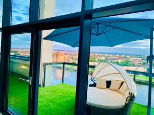 a chair sitting on a balcony with an umbrella at Glasgow City Centre - The PENTHOUSE with RiverViews - (Duplex, 3 Bedrooms, 3 Bathrooms, 2 Living rooms/Kitchen, Private SKY Terrace, 2 Parkings, Top Floor, Huge - 2100 sq ft, SECC HYDRO) in Glasgow