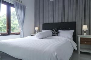 - une chambre avec un grand lit blanc et une fenêtre dans l'établissement Sayana Homestay, à Sleman