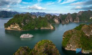 
a boat traveling down a river next to a mountain at Le Theatre Cruises - Wonder on Lan Ha Bay in Ha Long
